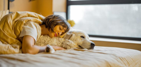 Persona durmiendo junto a su perro en la cama de casa de forma tranquila y cómoda